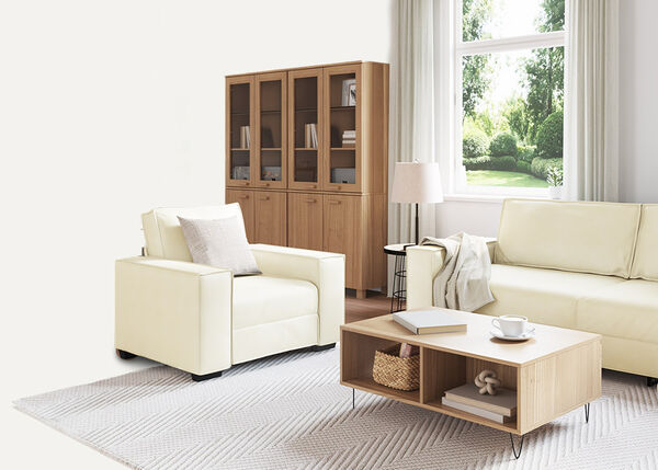 Hvit 2-seters sofa med puter og et pledd.