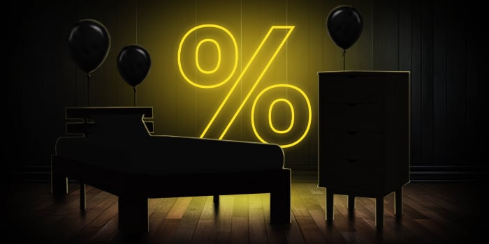  Svart seng og kommode med svarte ballonger foran et lyst gult prosenttegn på et mørkt tregulv.